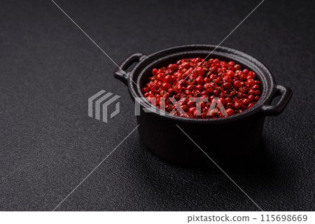 Spice, allspice peas in red or pink color in a bowl on a black concrete background 115698669