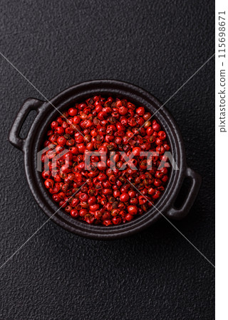 Spice, allspice peas in red or pink color in a bowl on a black concrete background 115698671