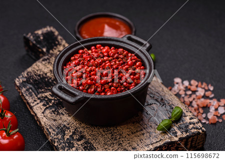 Spice, allspice peas in red or pink color in a bowl on a black concrete background 115698672
