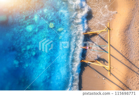 Aerial view of woman on the swing, beautiful blue sea with waves 115698771