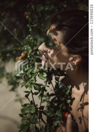 Woman with Green Leaves and Shadows Casting on Her Face surrounded by Nature and Sunlight 115698816