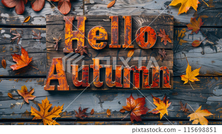 A rustic wooden surface with metal letters spelling Hello Autumn surrounded by fallen autumn leaves 115698851