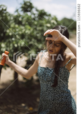 A young woman is happily drinking a cool beverage outdoors in the sunshine of summer 115698882