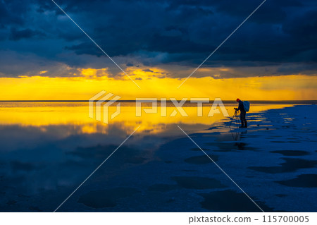 Photographer capturing sunset over reflective tranquil lake landscape Photographer capturing sunset over reflective tranquil lake landscape 115700005