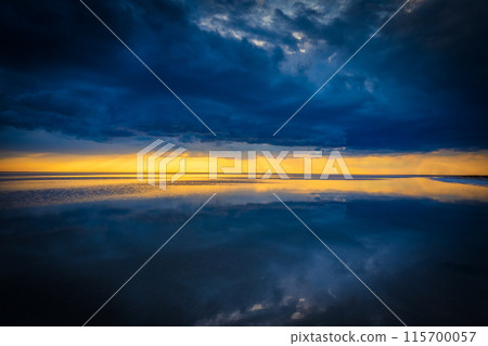 Stunning sunset over a calm reflective ocean with dramatic clouds 115700057