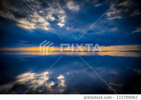 Dramatic sunset over calm ocean with reflective clouds 115700062