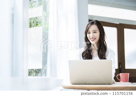 Young woman teleworking in a cafe 115701156