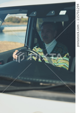A man in his 70s driving a car A man in his 70s driving a car 115701294