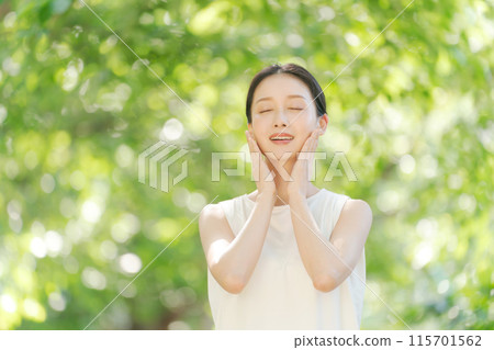一個女人在綠樹中微笑的美麗 一個女人在綠樹中微笑的美麗 115701562