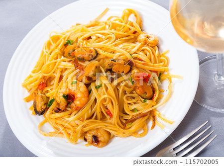 Deliciously pasta of shrimps, mussels and fresh greens at plate 115702005