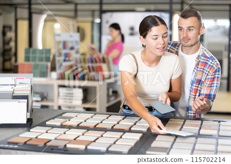 Couple man and woman looking at tile samples in store Couple man and woman looking at tile samples in store 115702214