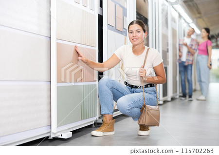 Young woman chooses tiles in hardware store Young woman chooses tiles in hardware store 115702263
