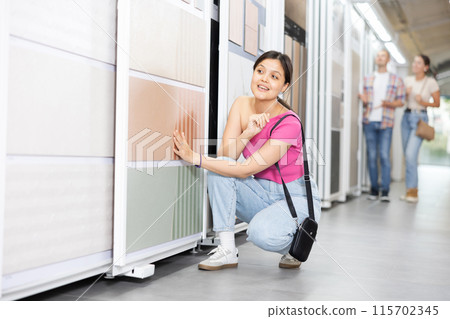 Positive woman wants to buy stone technical tiles for flooring or wall cladding in the materials department of hardware store 115702345