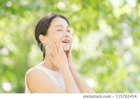 Female beauty touching her cheek among the fresh greenery 115702454