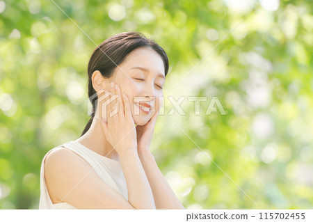 Female beauty touching her cheek among the fresh greenery 115702455