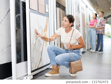 Young woman chooses tiles in hardware store 115702473