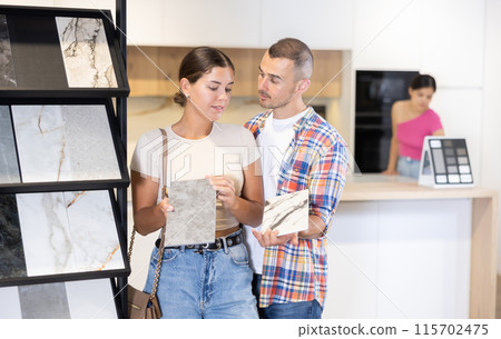Married couple discussing the color of ceramic tiles for the bathroom in hardware store 115702475