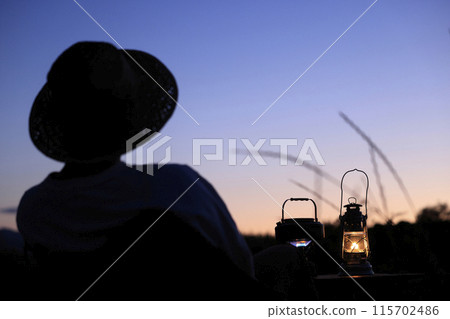A man on a solo camp watching the sunset 115702486