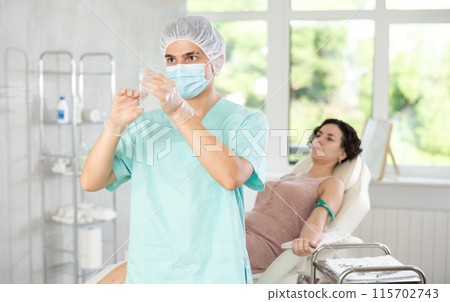 Doctor anesthetist checks the syringe before injection to patient Doctor anesthetist checks the syringe before injection to patient 115702743