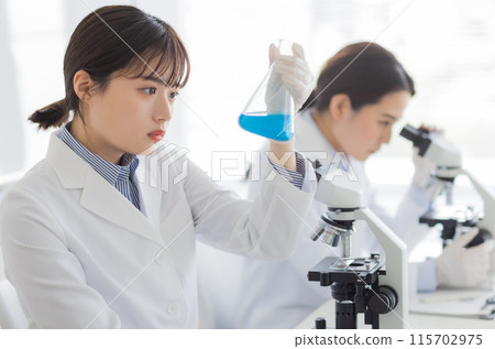 Woman in a white coat doing research Experiment Microscope 115702975