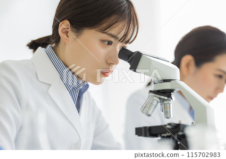 Woman in a white coat doing research Experiment Microscope 115702983