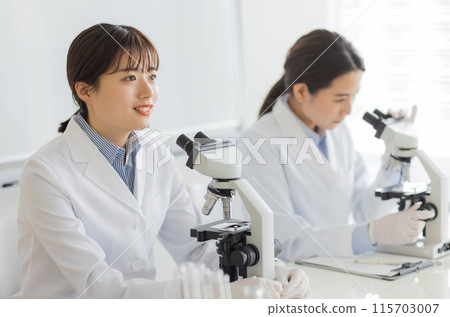 Woman in a white coat doing research Experiment Microscope 115703007