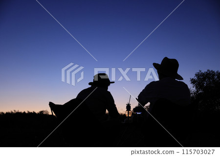 Silhouette of two men enjoying camping at sunset 115703027