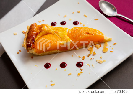 Slice of peach shortcrust custard tart with sliced almonds Slice of peach shortcrust custard tart with sliced almonds 115703091