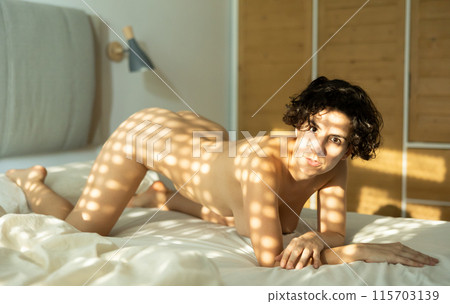 Adult nude woman kneeling on bed 115703139