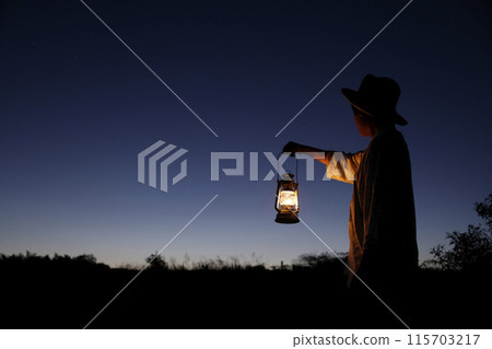 A man holding a lantern in the twilight A man holding a lantern in the twilight 115703217