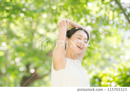 一個女人在綠樹叢中伸展身體 115703323