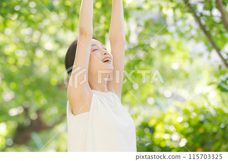 一個女人在綠樹叢中伸展身體 115703325