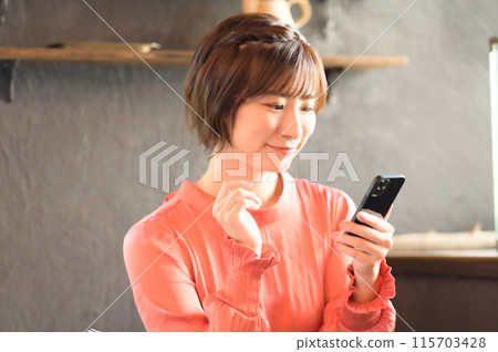 A woman watching a smartphone at a cafe A woman watching a smartphone at a cafe 115703428
