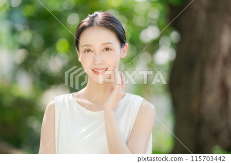 Female beauty touching her cheek among the fresh greenery 115703442