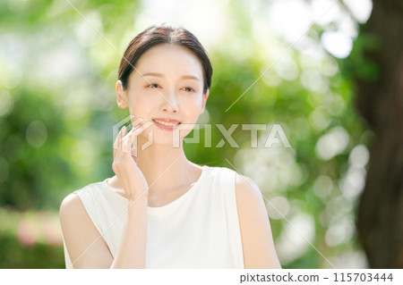 一個女人在新鮮的綠色植物中撫摸臉頰的美麗 一個女人在新鮮的綠色植物中撫摸臉頰的美麗 115703444