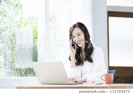 Young woman teleworking computer smartphone call phone 115703473