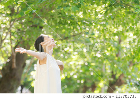 A woman taking a deep breath in the greenery 115703733
