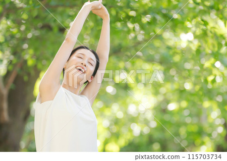 A woman taking a deep breath in the greenery A woman taking a deep breath in the greenery 115703734