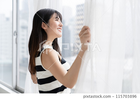 Woman opening curtain 115703896