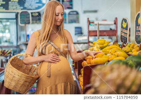 A pregnant woman is at a fruit stand in a grocery store Pregnant woman buying organic vegetables and fruits at Mexican style farmers market 115704050