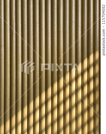 Wooden interior wall with shadows coming through the window. 115704082
