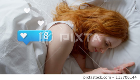Image of social media reactions over caucasian woman using smartphone in bed 115706144