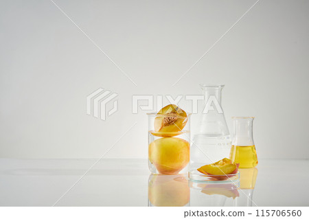 Minimalist style photo with theme of peach fruits in laboratory, from front angle on white background. Some types of lab glassware placed together on the left side of table, containing fresh peaches Minimalist style photo with theme of peach fruits in laboratory, from front angle on white background. Some types of lab glassware placed together on the left side of table, containing fresh peaches 115706560