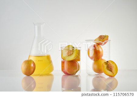 Peach scent cosmetic advertising template with laboratory concept, different types of glassware containing fresh peach and peach essence, placed on white table. Blank space for text, front view Peach scent cosmetic advertising template with laboratory concept, different types of glassware containing fresh peach and peach essence, placed on white table. Blank space for text, front view 115706570