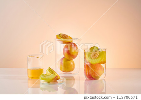 The promotional photo of peach ingredient in laboratory, in center of white table displaying some beakers, which contains ripe peach and yellow extract, in front placing a petri dish of sliced peach The promotional photo of peach ingredient in laboratory, in center of white table displaying some beakers, which contains ripe peach and yellow extract, in front placing a petri dish of sliced peach 115706571