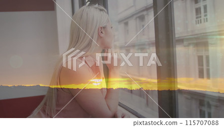 Image of sunset over thoughtful smiling caucasian woman looking out of window in office Image of sunset over thoughtful smiling caucasian woman looking out of window in office 115707088