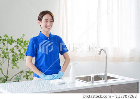 A female staff member of a cleaning company cleaning the kitchen (house cleaning/housekeeping service) 115707268