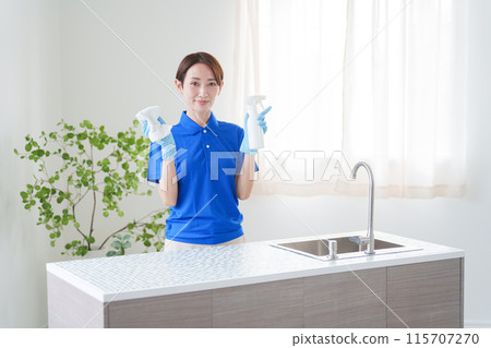 A female staff member of a cleaning company cleaning the kitchen (house cleaning/housekeeping service) 115707270