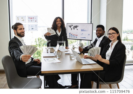 Diverse business team celebrating financial success with money in office 115709476