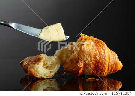 Fresh baked croissant with butter on a black background. 115711394